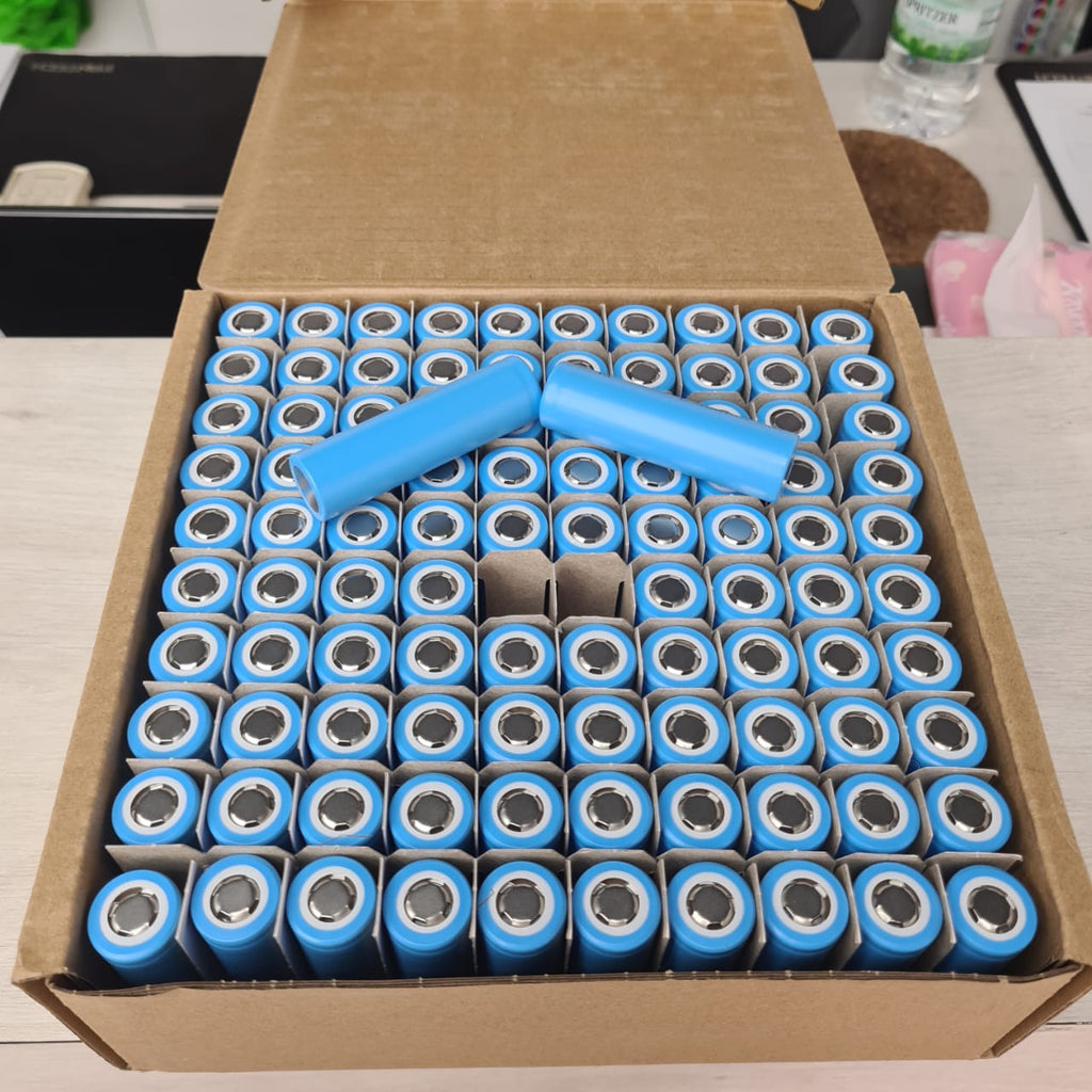 Box filled with blue cylindrical batteries on a light-colored surface.