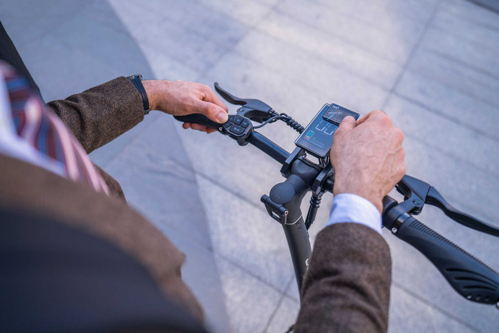 Person operating an electric scooter with a digital display on a blurred background